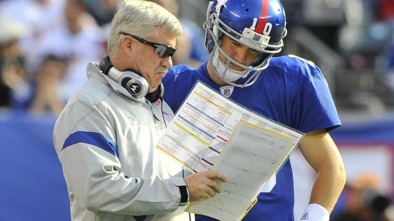 Kevin Gilbride and Eli manning discuss play selection during a...