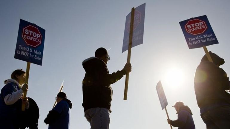 Postal workers and and their supporters demonstrate outside of a...