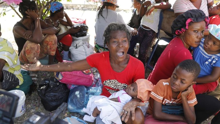 Women and children gather outside a police station after fleeing...