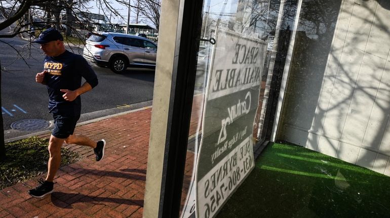 A runner passes the shuttered Sayville Florist on Railroad Avenue...