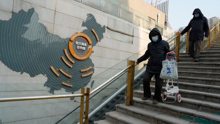 Residents walk through a partially shuttered Evergrande commercial complex in...