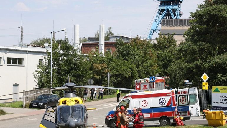 Rescuers transport an injured miner to an airborne ambulance near...