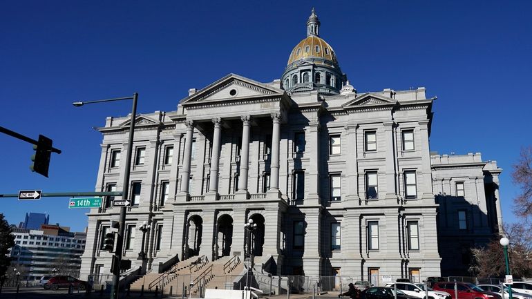 A lone cyclist passes by Colorado's State Capitol building, Friday,...