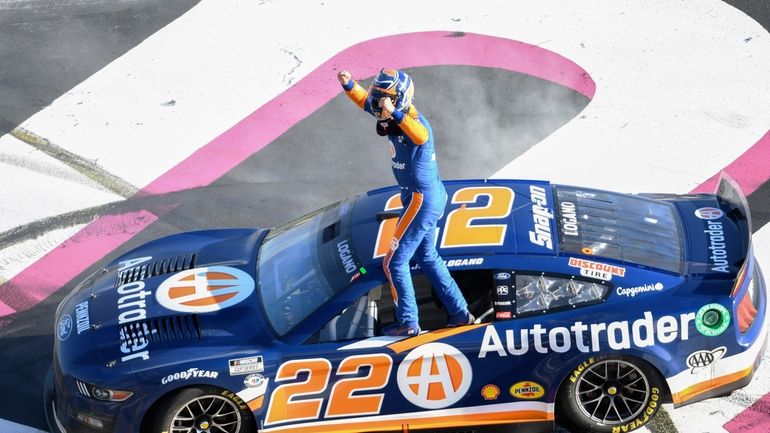 Joey Logano stands on his car after winning the NASCAR...