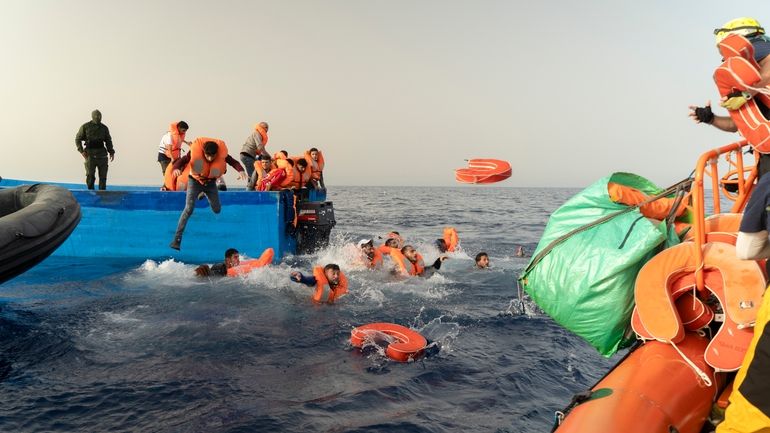 Rescue personnel of the SOS Mediterranee's volunteers, right, help transfer...