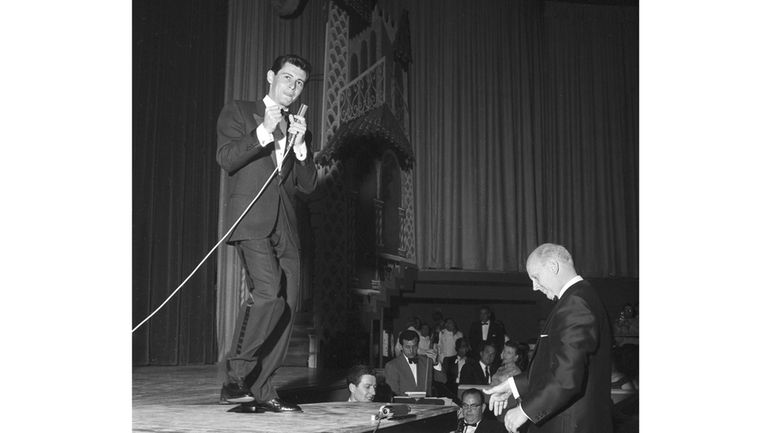 Eddie Fisher uses the top of a grand piano as...