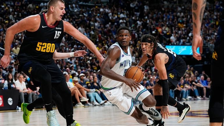 Minnesota Timberwolves guard Anthony Edwards, center, drives to the basket...