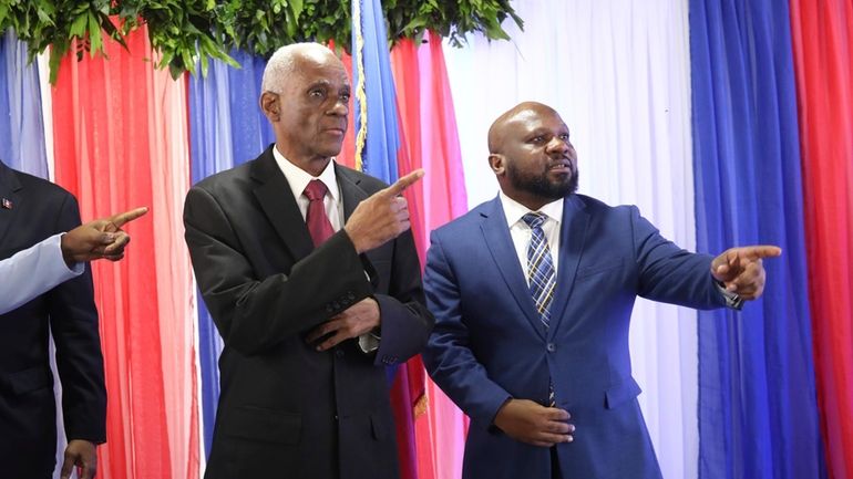 Edgard Leblanc Fils, left, and Smith Augustin prepare to pose...