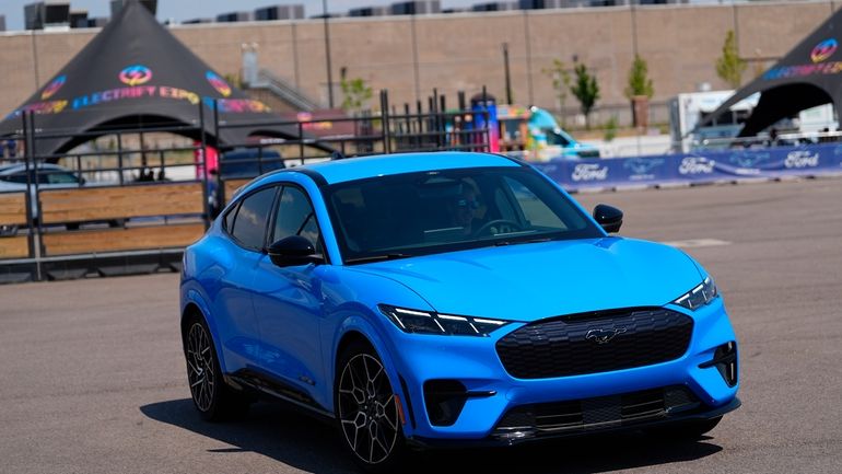 A motorist puts an electric 2024 Ford Mustang Mach-E through...