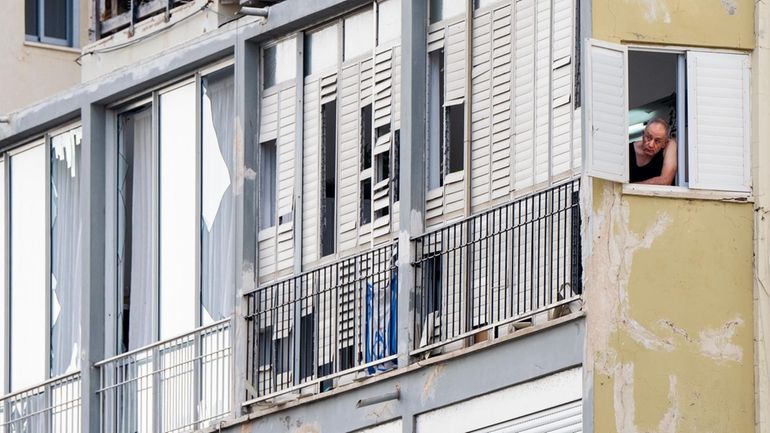 A man watches from his window at the scene of...