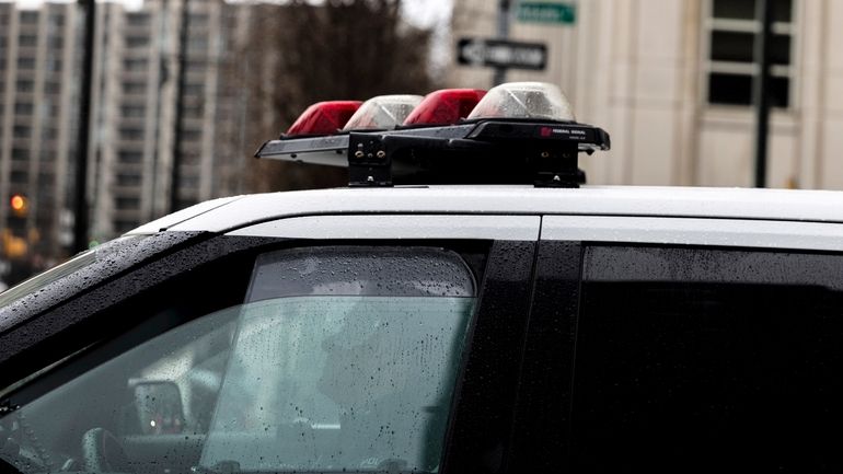 A police officer sits in a car near the Brooklyn...