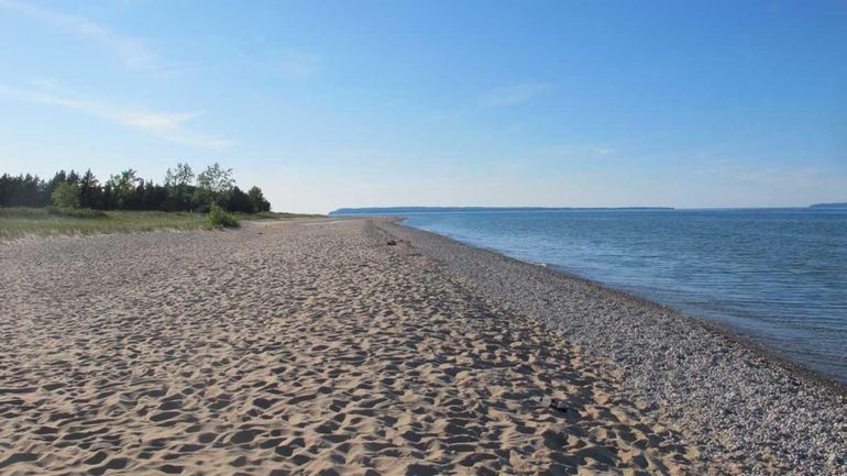 A lengthy stretch of sandy Lake Michigan beach is deserted...