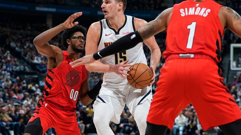 Denver Nuggets center Nikola Jokic, center, drives the lane as...