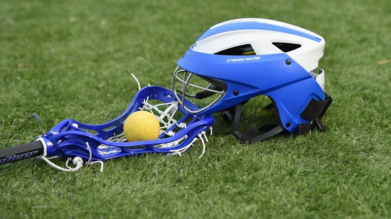 A lacrosse helmet, stick and ball on the turf at...