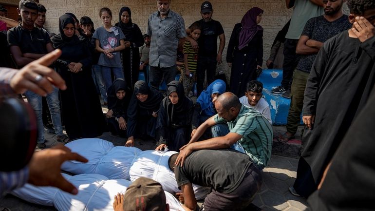 Palestinians mourn over the bodies of their relatives killed in...