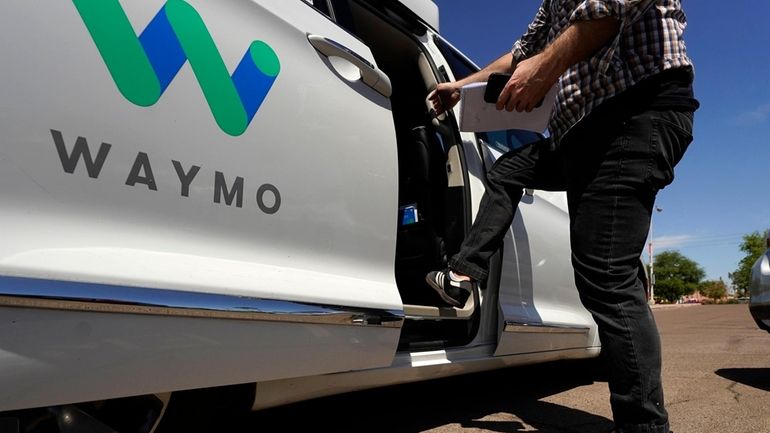 A Waymo minivan arrives to pick up passengers for an...