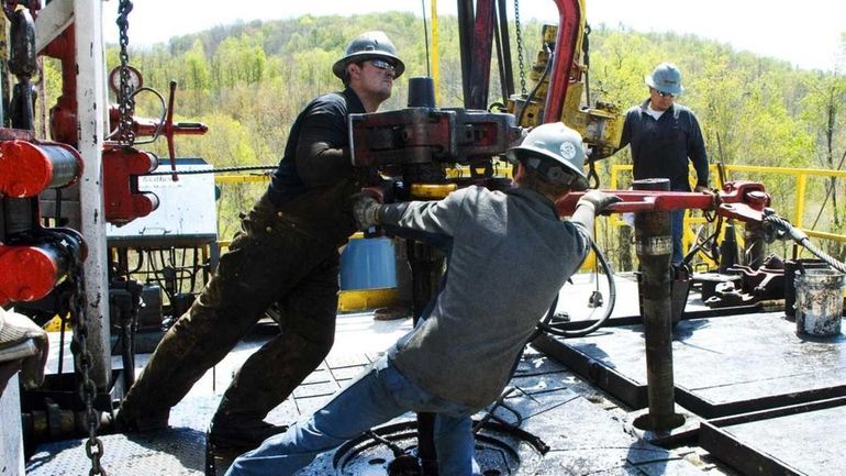 Workers move a section of well casing into place at...