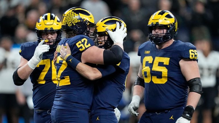 Michigan quarterback J.J. McCarthy is congratulated by teammates Kechaun Bennett...