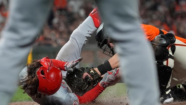 Cincinnati Reds' Stuart Fairchild, left, slides home to score on...