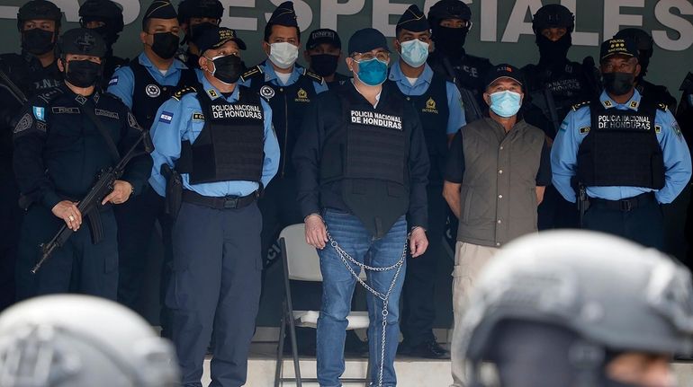 Former Honduran President Juan Orlando Hernandez, center in chains, is...