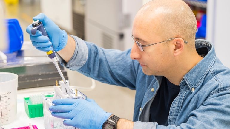 A lab technician prepares DNA samples for analysis at Complete...