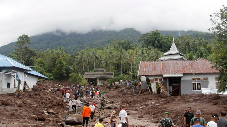 Rescuers and villagers search for missing people, following a flash...