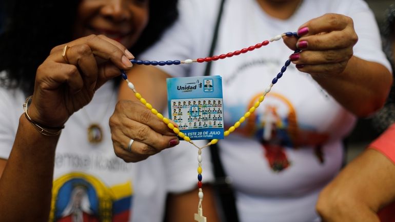 Opposition supporters hold a rosary with a flyer showing presidential...