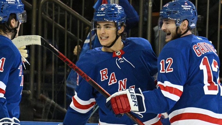 Rangers defenseman Braden Schneider, center, celebrates his goal with left...