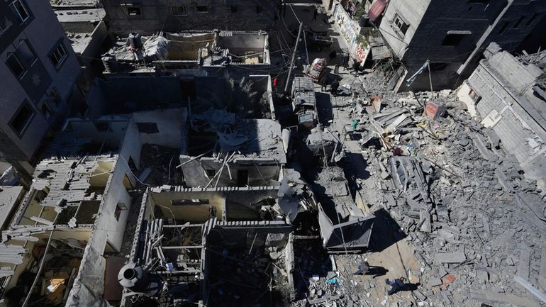 Palestinians inspect the rubble of destroyed buildings after an Israeli...