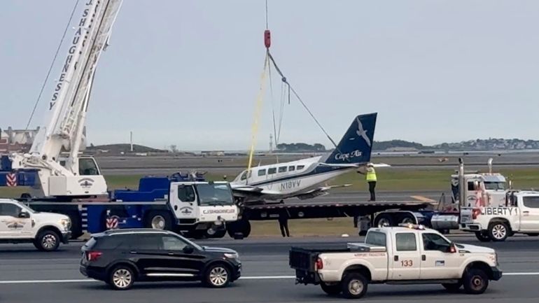 Officials remove a small plane that landed at Logan International...