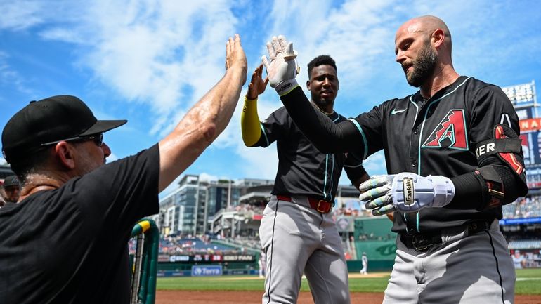 Arizona Diamondbacks manager Torey Lovullo, left, congratulates Diamondbacks' Christian Walker...