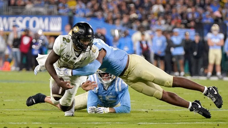 Colorado quarterback Shedeur Sanders, left, fumbles the ball as UCLA...