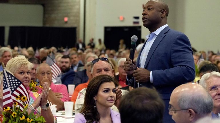 Republican presidential candidate Sen. Tim Scott, R-S.C., right, walks by...