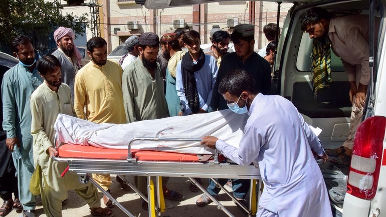 Volunteers and relatives load the body of a passenger, who...