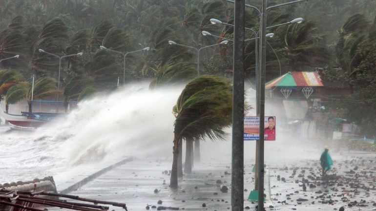 A resident walks past high waves pounding the sea wall...