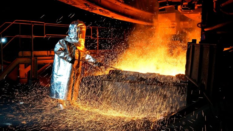 A worker in a protective suit pokes a metal rod...