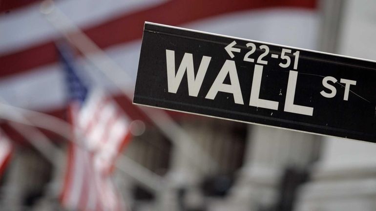 A Wall Street sign is mounted near the flag-draped facade...