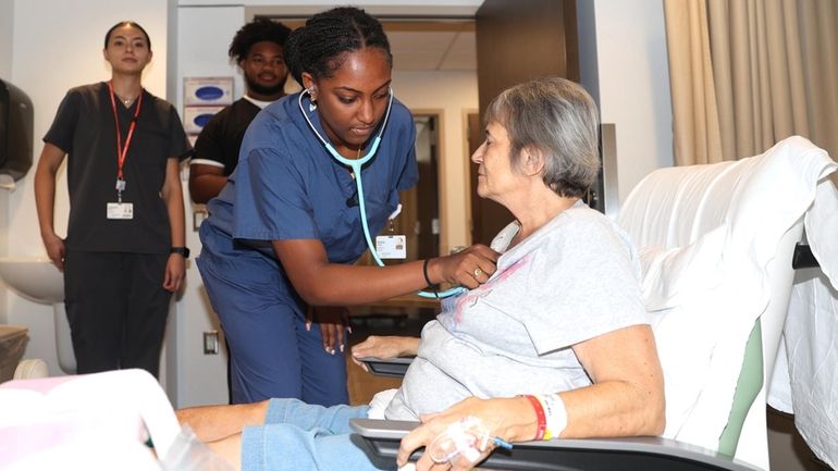 Kezia White checks the blood pressure of Barbara Pollack, 66, of...