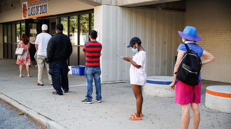 Voters wait in line to cast their ballots in New...