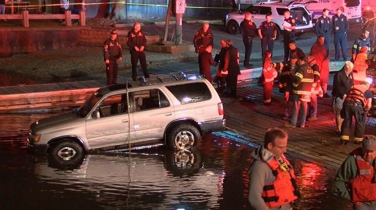 A vehicle is removed from the water in Port Jefferson...