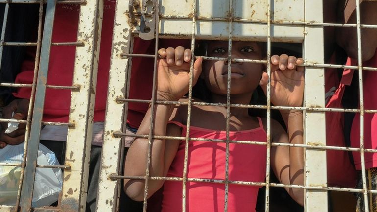 A child stands amid people who were detained for deportation...