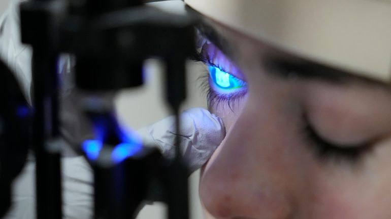 Dr. Alfonso Sabater, checks Antonio Vento Carvajal's eye under a...