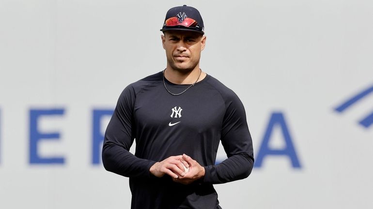 Giancarlo Stanton #27 of the New York Yankees walks on...