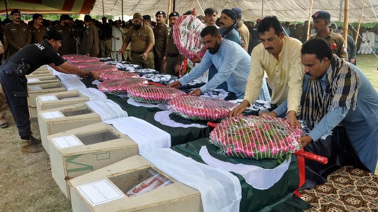 People place wreath on the caskets of police officers, who...