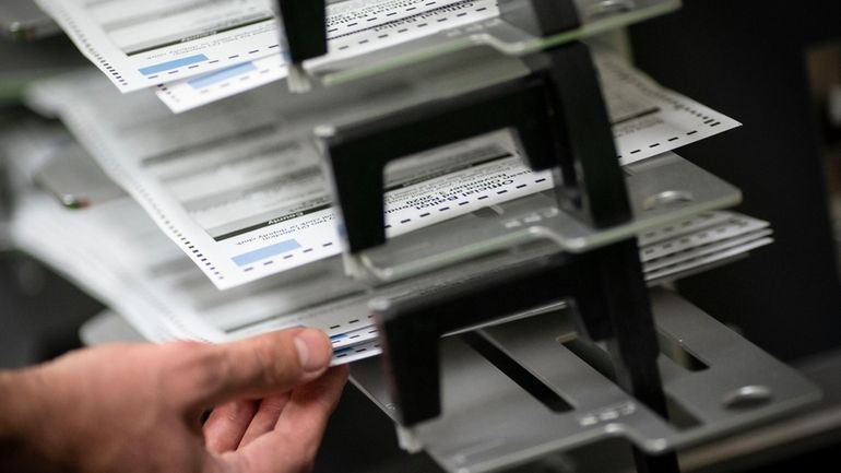 Poll workers sort out early and absentee ballots at the...