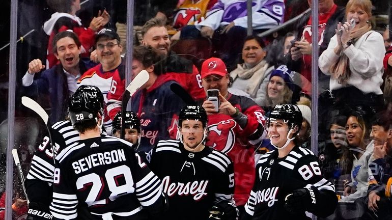 New Jersey Devils' Jack Hughes (86) celebrates with teammates after...