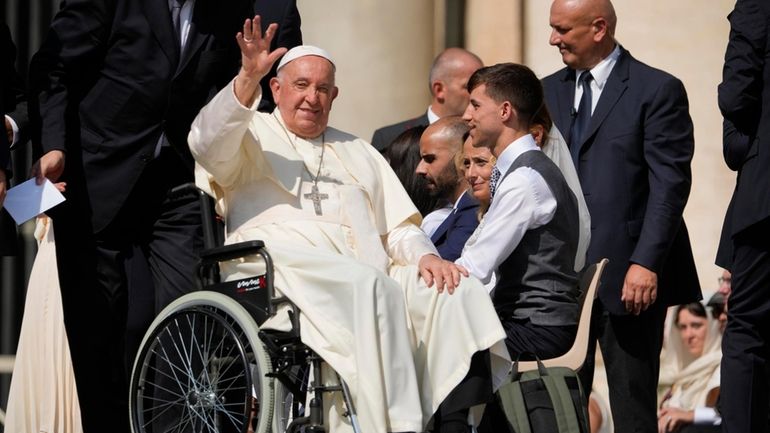 Pope Francis waves as he leaves after his weekly general...