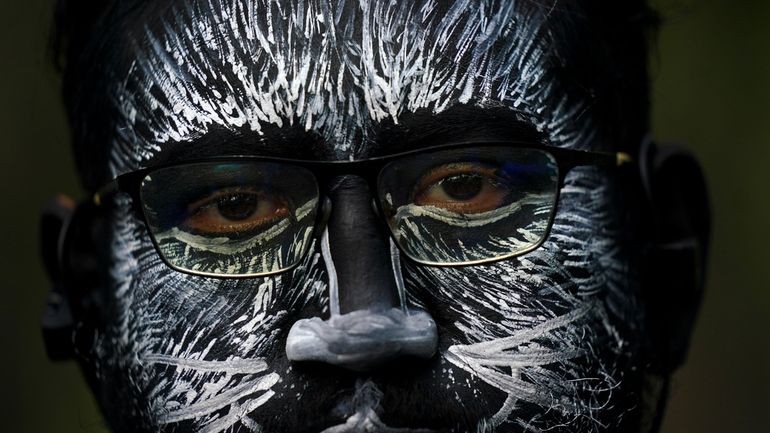 A visitor, his face painted to represent a zebra, during...