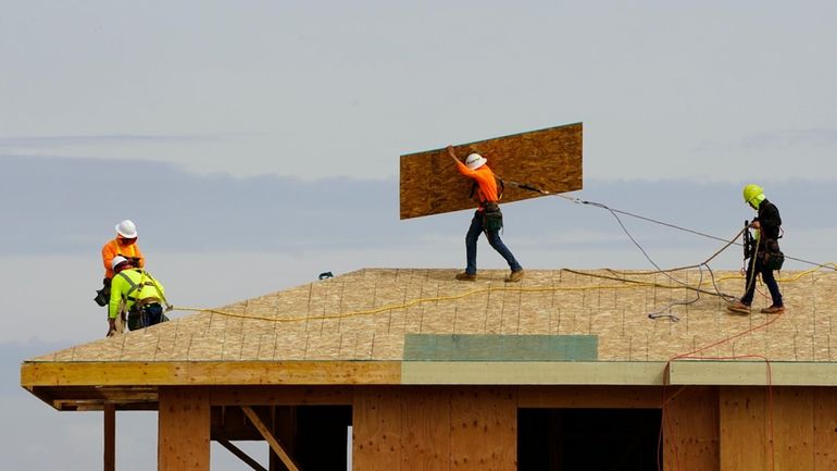 Work is done on the roof of a building under...