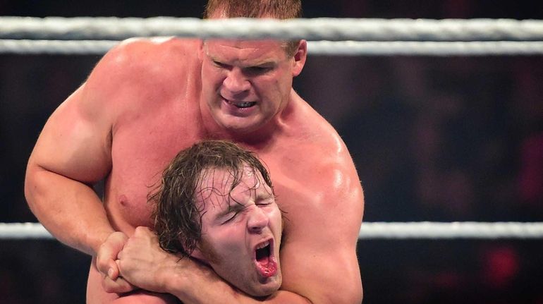 WWE Superstar Kane holds a chin lock on Dean Ambrose...